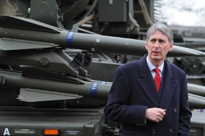 Defence Secretary Philip Hammond stands in front of his very hard military force.